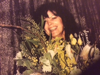 Carol smiling with a bouquet of flowers